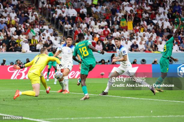 Ismaila Sarr of Senegal shoots under pressure from Jordan Pickford of England during the FIFA World Cup Qatar 2022 Round of 16 match between England...