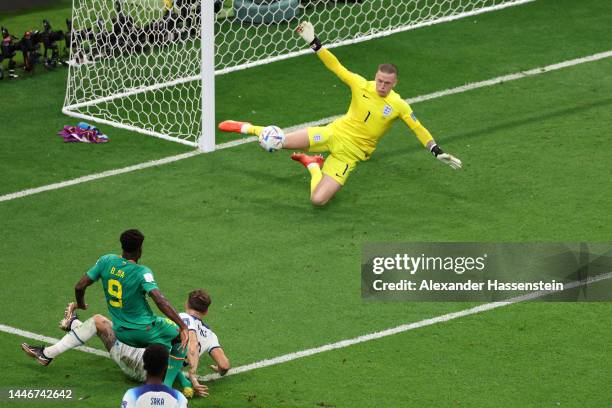 Boulaye Dia of Senegal shoots past John Stones of England as Jordan Pickford makes a save during the FIFA World Cup Qatar 2022 Round of 16 match...