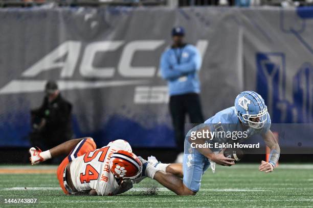 Jeremiah Trotter Jr. #54 of the Clemson Tigers trips up Drake Maye of the North Carolina Tar Heels in the third quarter during the ACC Championship...