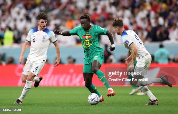 Famara Diedhiou of Senegal controls the ball against Declan Rice and John Stones of England during the FIFA World Cup Qatar 2022 Round of 16 match...