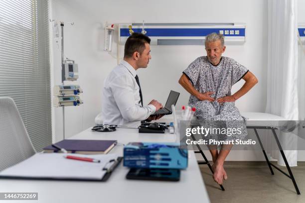 doctor listens intently to her senior male patient - hernia stock pictures, royalty-free photos & images