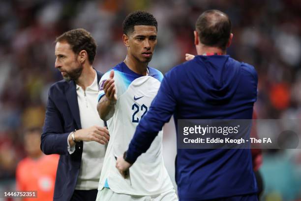 Jude Bellingham of England interacts with Gareth Southgate, Head Coach of England, and Steve Holland, Assistant Coach of England as he is substituted...