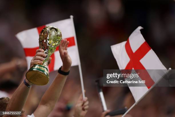 Detailed view of a replica FIFA World Cup trophy held by England fans after the team's victory during the FIFA World Cup Qatar 2022 Round of 16 match...