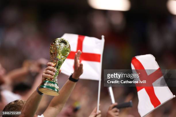 Detailed view of a replica FIFA World Cup trophy held by England fans after the team's victory during the FIFA World Cup Qatar 2022 Round of 16 match...