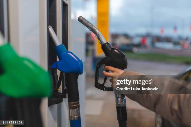 nahaufnahme einer jungen frau mit einer schwarzen (diesel-)gasdüse an einer tankstelle - diesel kraftstoff stock-fotos und bilder