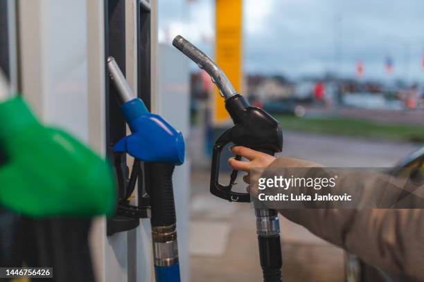 close-up of a young woman holding a black (diesel) gas nozzle at a gas station - diesel imagens e fotografias de stock