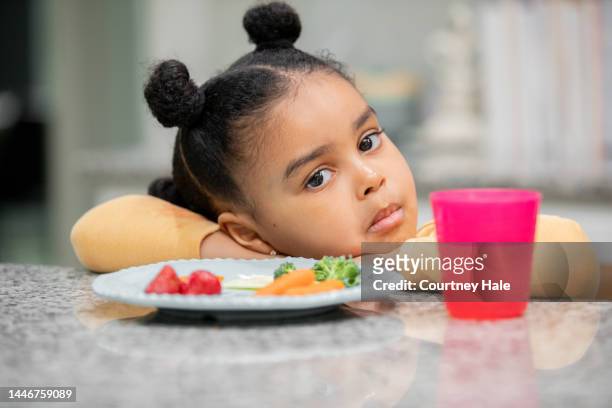 little girl is picky eater who is refusing to eat healthy meal at kitchen counter - picky eater stockfoto's en -beelden