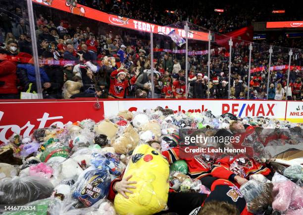 Keagan Slaney, Riley Fiddler-Schultz and Brayden Peters of the Calgary Hitmen lay down in a pile of plush toys after their goal on the Moose Jaw...
