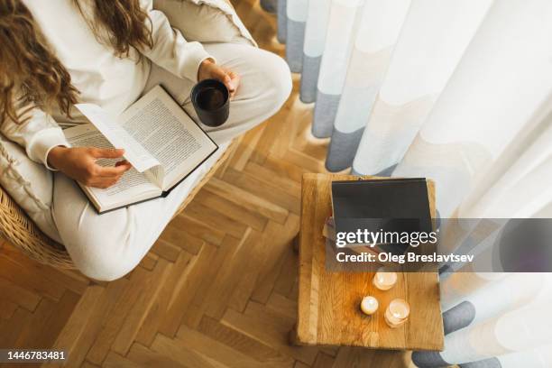 overhead view of woman hands holding cup of black coffee and book. reading at home - nachtwäsche stock-fotos und bilder