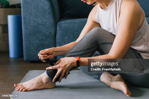woman putting ankle weights on - zwaar stockfoto's en -beelden