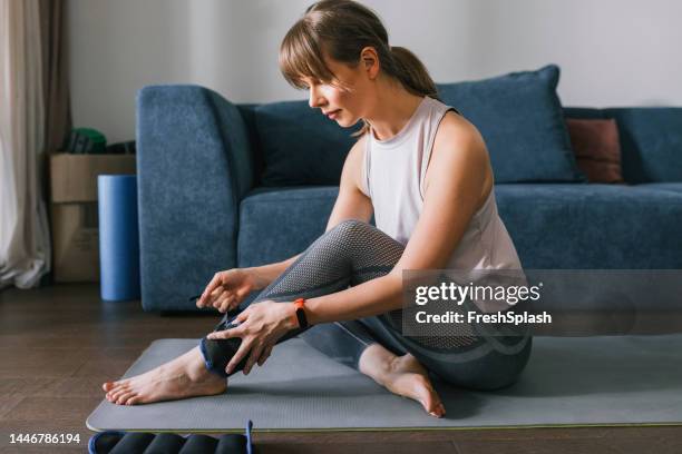 woman putting ankle weights on - tornozelo imagens e fotografias de stock