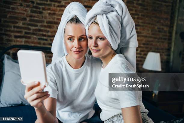 a happy beautiful blonde woman taking care of her and her daughter's skin - girl in mirror stock pictures, royalty-free photos & images