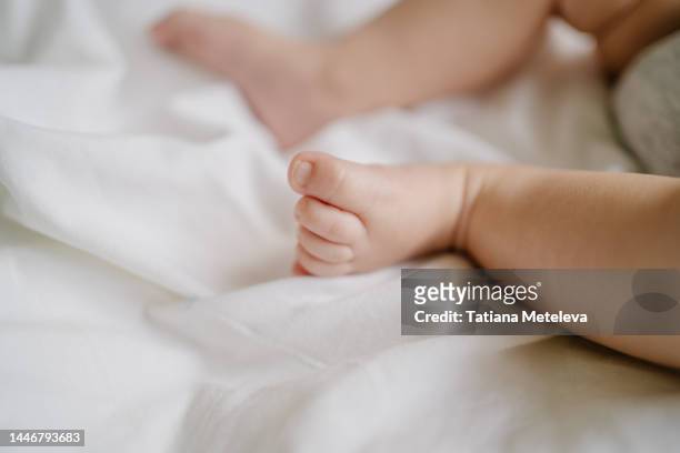 baby flat foot condition. close up newborn bare feet of a baby lying in white linen in bed. - bare kids foto e immagini stock
