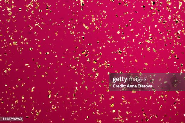 festive golden confetti on dark red background. merry christmas and a happy new year. demonstrating viva magenta - color of the year 2023 - confetti gold ストックフォトと画像