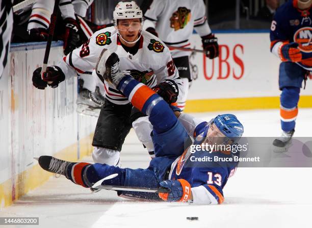 Philipp Kurashev of the Chicago Blackhawks trips up Mathew Barzal of the New York Islanders during the third period at the UBS Arena on December 04,...