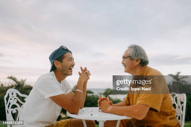 senior father and adult son chatting on patio - masculinidade moderna imagens e fotografias de stock