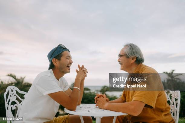 senior father and adult son chatting on patio - família de duas gerações imagens e fotografias de stock