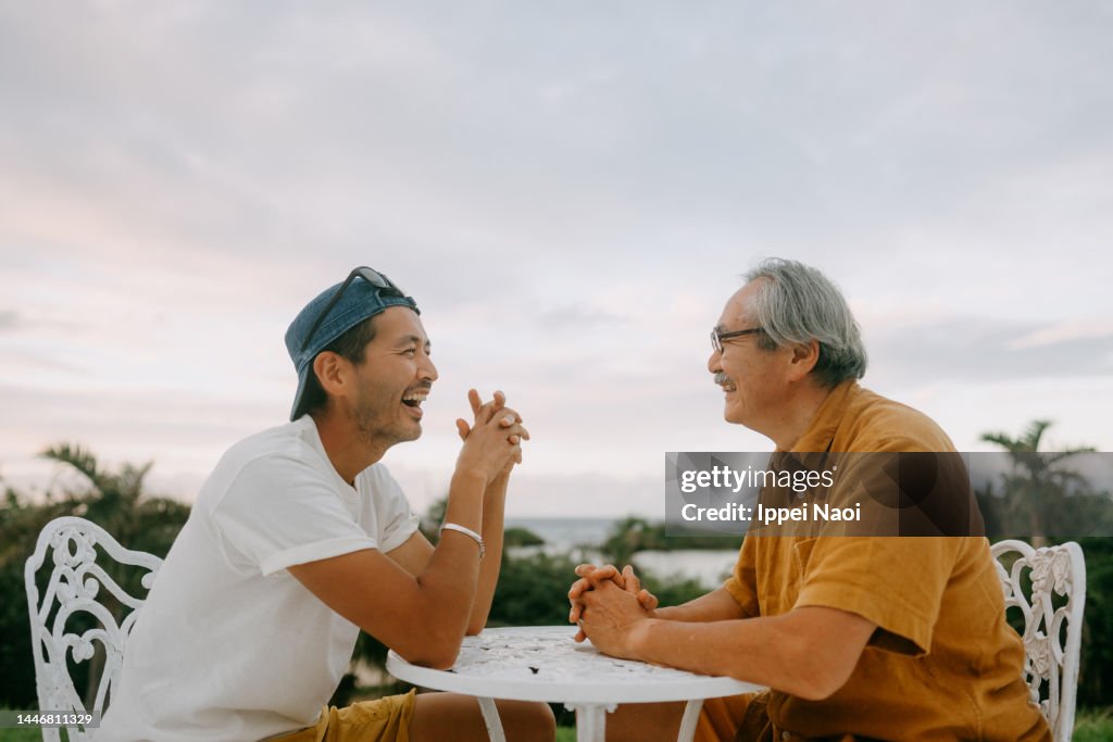 Senior father and adult son chatting on patio