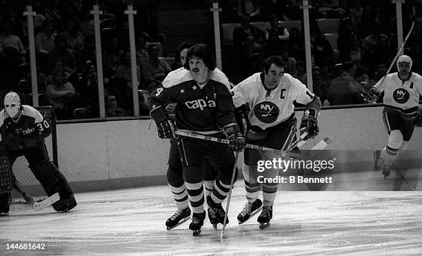 Bill Mikkelson of the Washington Capitals and Ed Westfall of the New York Islanders skate on the ice on Febuary 8, 1975 at the Nassau Coliseum in...