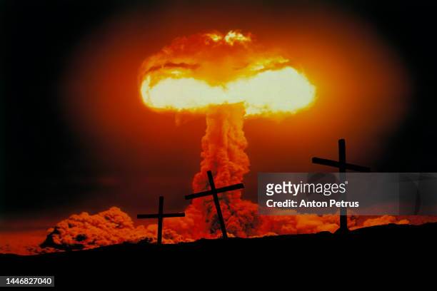 nuclear explosion with mushroom cloud on the background of crosses. nuclear war threat concept - paddenstoelenwolk stockfoto's en -beelden