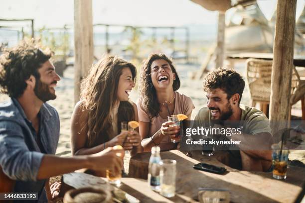 parejas alegres hablando en un día de verano en un bar de playa. - friendship fotografías e imágenes de stock