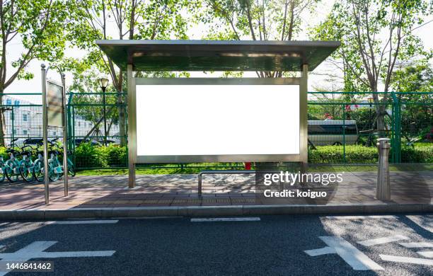 bus stop and blank billboard in front of asphalt road - haltestelle stock-fotos und bilder