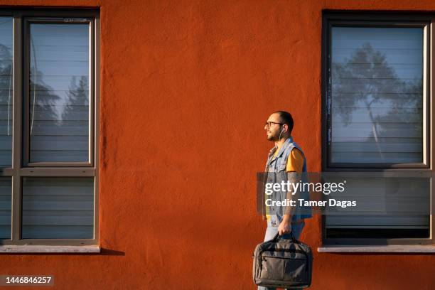 a man walking past an orange wall - walking past office wall stock pictures, royalty-free photos & images