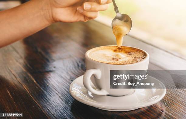 someone using a spoon for scooping creamy on the surface of latte coffee before drinking. - coffee foam imagens e fotografias de stock