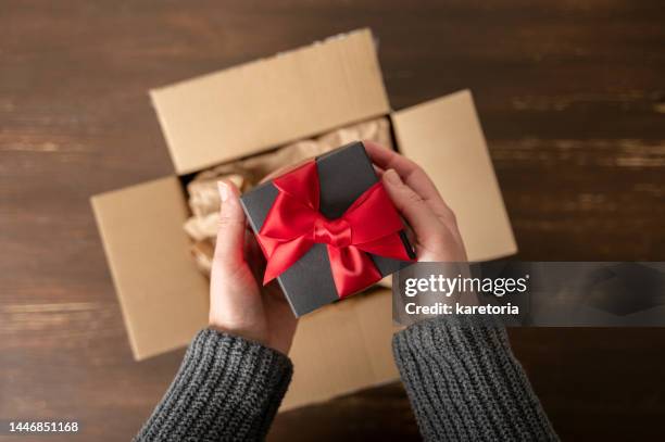 woman hands taking gift box out of parcel - black craft paper stock pictures, royalty-free photos & images