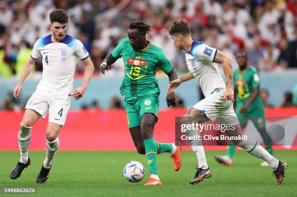 Famara Diedhiou of Senegal controls the ball against Declan Rice and John Stones of England during the FIFA World Cup Qatar 2022 Round of 16 match...