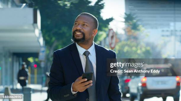 black ceo, businessman walking in city and smartphone in hand for gps navigation, social media and online conversation. confident, mature and smiling senior executive on urban town street with phone - assertiveness stock pictures, royalty-free photos & images