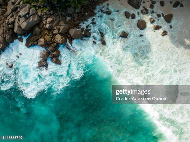 aerial view top down seashore. waves crashing on rock cliff. beautiful dark sea surface in sunny day summer background amazing seascape top view seacoast at intendance beach, mahe seychelles - jade stock pictures, royalty-free photos & images