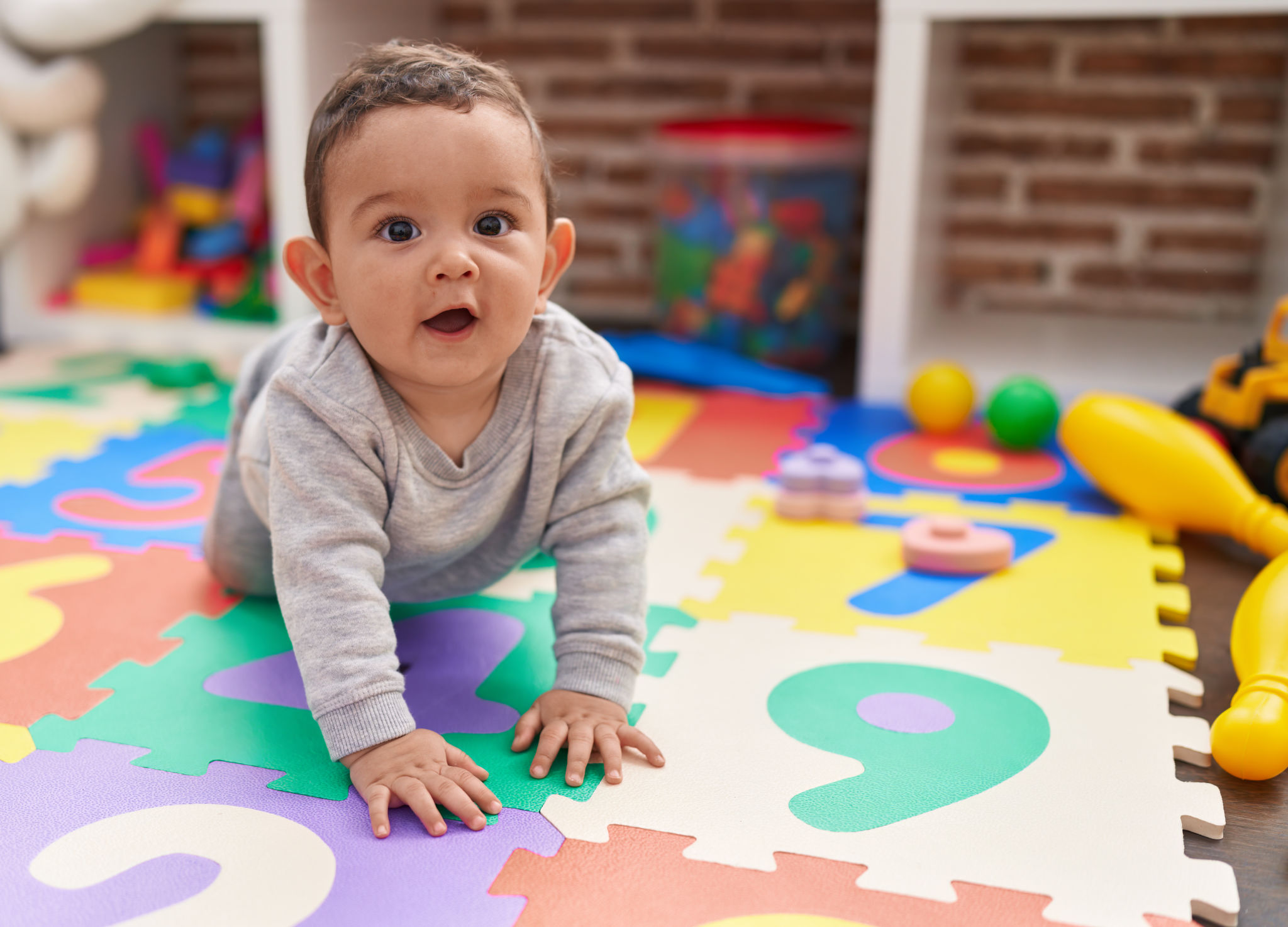 Bambino ispanico adorabile che striscia sul pavimento all'asilo Bambino ispanico adorabile che striscia sul pavimento all'asilo