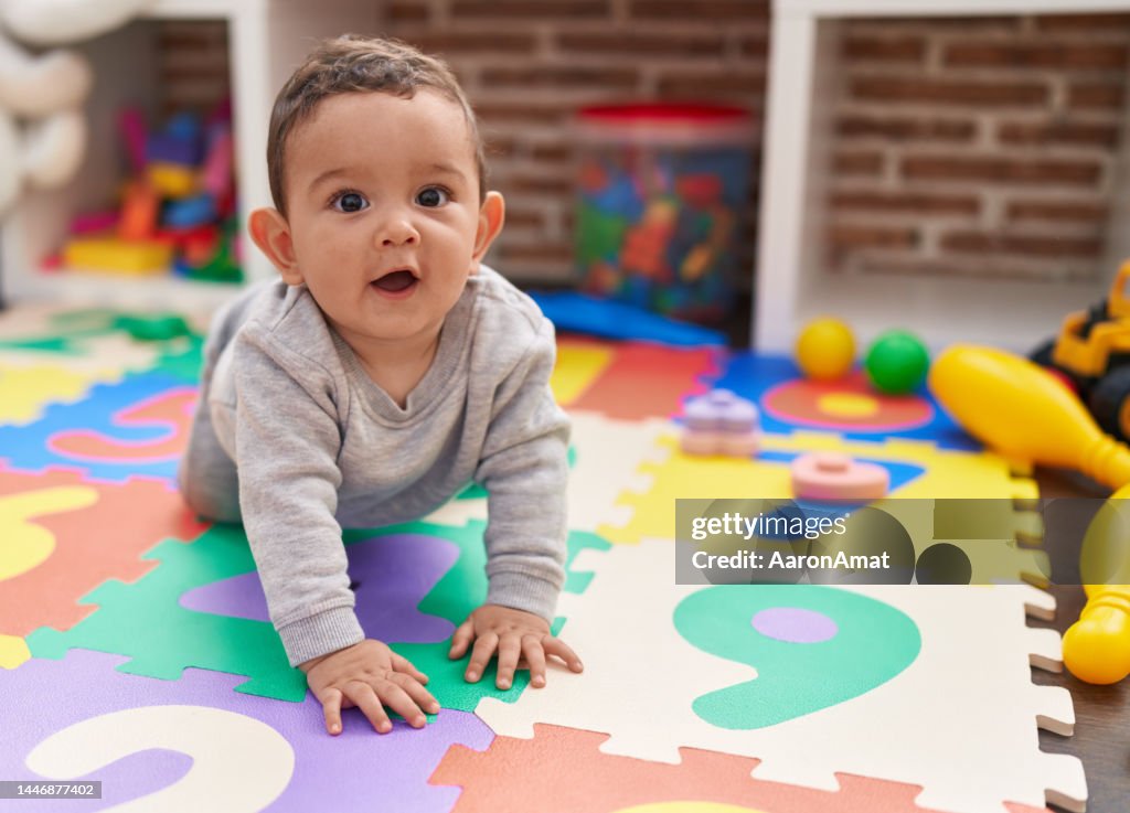 Adorável bebê hispânico rastejando no chão no jardim de infância