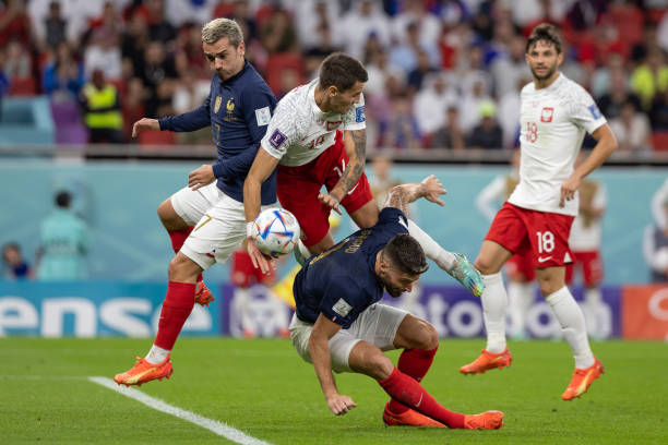 Olivier Giroud of France and Antoine Griezmann of France tangle with Jakub Kiwior of Poland during the FIFA World Cup Qatar 2022 Round of 16 match...