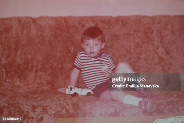 portrait of a boy sitting on a couch with his car toy - balkans bildbanksfoton och bilder