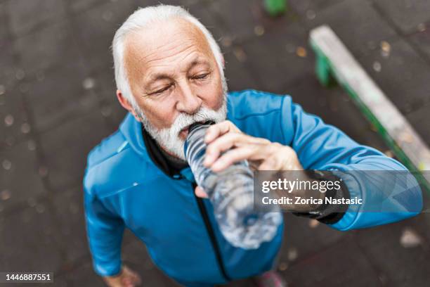 senior man drinking water while exercising outdoors - thirsty stock pictures, royalty-free photos & images