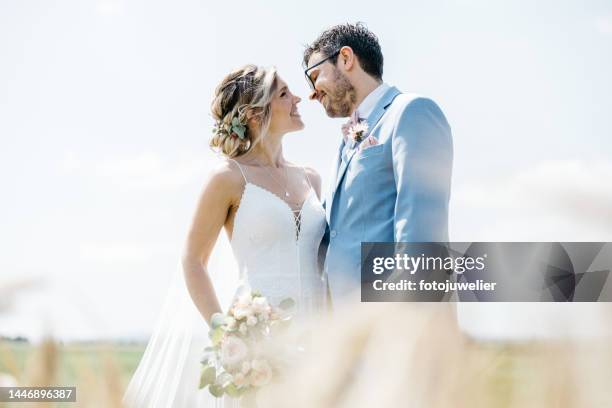romantic outdoor shooting with bride and groom in a field in summer - newlywed stock pictures, royalty-free photos & images