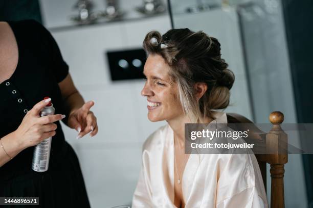 bride getting ready for wedding with stylist using hairspray and curlers - hair curlers stockfoto's en -beelden