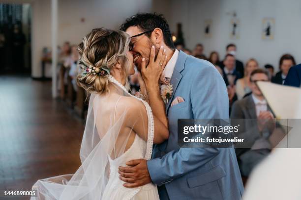 bride and groom kissing at the wedding ceremony in the church - pas getrouwd stockfoto's en -beelden