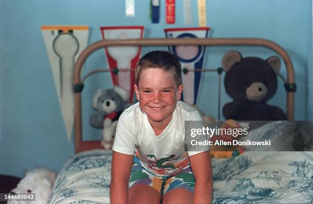 smiling boy on his bed in his bedroom - boy freckle stock pictures, royalty-free photos & images