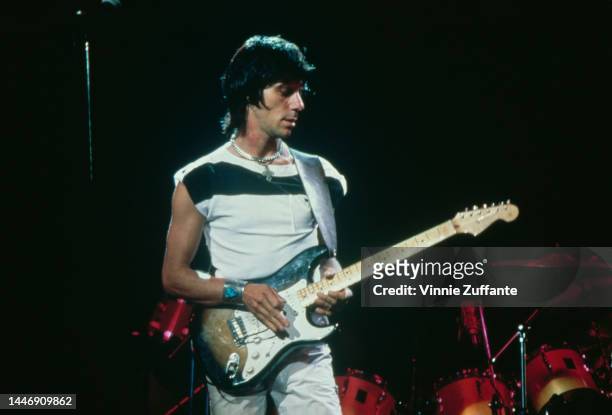 British guitarist and songwriter Jeff Beck, wearing a white t-shirt with a horizontal stripe and white trousers, playing a Fender Stratocaster at a...