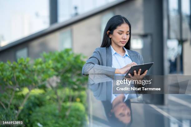 sustainable lifestyles in the workplace. side view of asian businesswomen using a tablet computer for a discussion of business data on a rooftop of a business office. - financial advisor virtual stock pictures, royalty-free photos & images