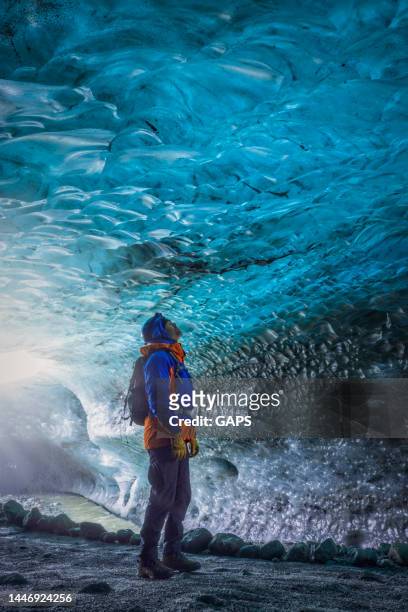 homem em pé em uma bela caverna de gelo azul da geleira vatnajökull na islândia - vatnajokull - fotografias e filmes do acervo
