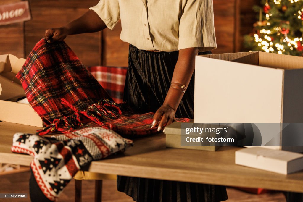 Young woman standing over a table and and folding clothes for Christmas donations