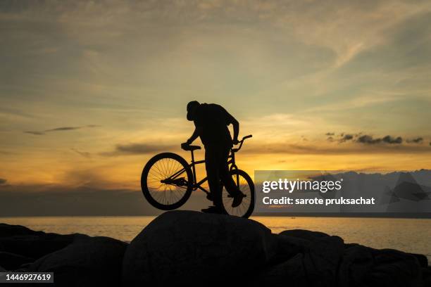 bmx , man and bicycle on rocky hill by the sea ,thailand , extreme sport concept. - bike wheel race stock pictures, royalty-free photos & images