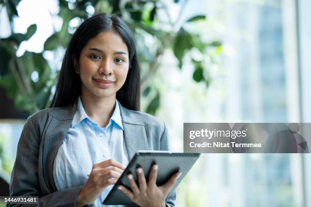 financial planning is key to success. portrait of an asian female financial advisor holding a tablet computer working in a financial business office to provide financial planning advice to her clients. - tax scrutiny stock pictures, royalty-free photos & images