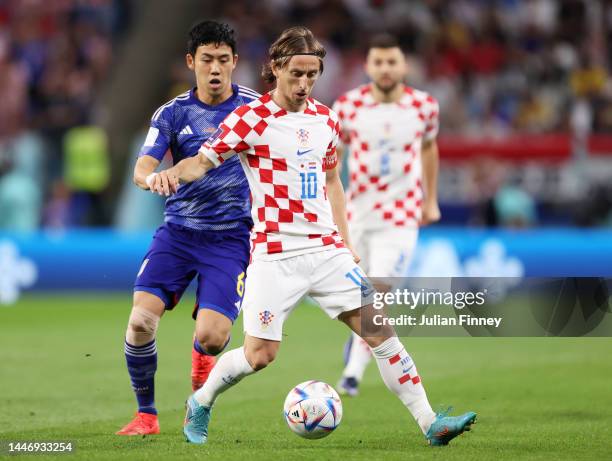 Luka Modric of Croatia is challenged by Wataru Endo of Japan during the FIFA World Cup Qatar 2022 Round of 16 match between Japan and Croatia at Al...