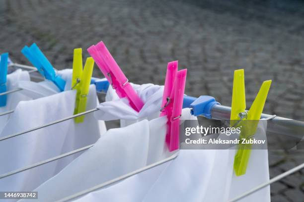 clean pillowcases, sheets and duvet covers hang on a rope outside on a sunny summer day. washed clothes, bed linen are dried hanging on the clothes dryer. clothespins for things close-up. the concept of homework, household duties. - wäscheklammer stock-fotos und bilder