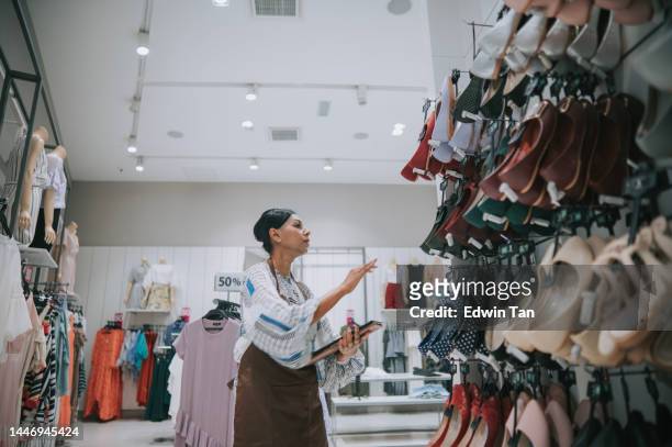 asian indian female boutique shop clothing store owner checking stock with digital tablet - shoe shop assistant stock pictures, royalty-free photos & images